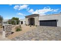Modern house exterior with desert landscaping, stone accents, and black garage door at 7528 E Windrose Dr, Scottsdale, AZ 85260
