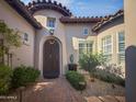 Charming arched entrance to a home with a secure wrought iron door, lush landscaping, and brick paver walkway at 8964 E Mountain Spring Rd, Scottsdale, AZ 85255