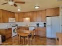 Well-lit kitchen features lots of wooden cabinets, a white refrigerator, and hardwood floors at 907 E Lancaster Cir, Florence, AZ 85132