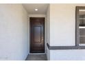 Inviting front entryway showcasing a sleek, dark-stained door, complemented by the textured exterior and framed window at 18220 W Daley Ln, Surprise, AZ 85387