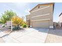 Two-story home with a tan stucco exterior, two-car garage, and low-maintenance desert landscaping at 1037 E Dust Devil Dr, San Tan Valley, AZ 85143