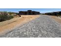 Long driveway made of gray pavers leading up to a modern home, surrounded by desert landscape at 13382 E Sand Hills Rd, Scottsdale, AZ 85255