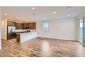Open-concept living room and kitchen with hardwood floors, stainless steel appliances, and natural light at 15760 W Pioneer St, Goodyear, AZ 85338