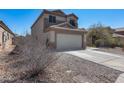Exterior showcasing the home's tan facade, two-car garage, and concrete driveway, complemented by desert landscaping at 1673 S 218Th Ave, Buckeye, AZ 85326