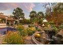 Lush backyard with a tranquil fountain, fire pit, and comfortable seating area surrounded by beautiful greenery at 22402 N 84Th Pl, Scottsdale, AZ 85255
