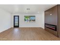 Bright living room with wood-look flooring, electric fireplace, modern accent wall, and a glass-paneled door at 7507 E Beatrice St, Scottsdale, AZ 85257