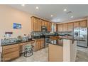 Spacious kitchen with stainless appliances, tile floors, wood cabinets, and an integrated workspace with a stool at 16526 W Calle Lejos --, Surprise, AZ 85387