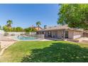 Expansive backyard with lush green grass, mature trees, and a fenced swimming pool at 4534 E Beverly Ln, Phoenix, AZ 85032
