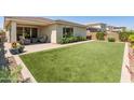 A beautiful outdoor oasis with manicured landscaping, a patio area, and lush synthetic lawn at 5962 E Abraham Ln, Phoenix, AZ 85054