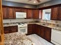 This kitchen features granite counters, cherry cabinets, white appliances and tile flooring at 6258 E Duncan St, Mesa, AZ 85205