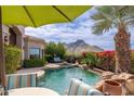 Inviting pool area with a natural rock waterfall and vibrant flowering shrubbery with mountain views at 11187 E De La O Rd, Scottsdale, AZ 85255