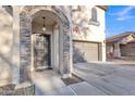 Close-up view of a charming home entrance, featuring a stone archway and decorative door at 40613 N Jerlyn Pl, San Tan Valley, AZ 85140