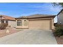 Tan single-story home featuring a two-car garage and xeriscaped front yard at 42370 W Hillman Dr, Maricopa, AZ 85138
