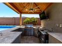 The outdoor kitchen is equipped with a built-in grill, sink, and counter space, perfect for summer gatherings at 45975 W Mountain View Rd, Maricopa, AZ 85139