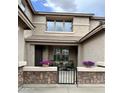 Inviting front porch with seating and decorative flower pots, set behind a charming stone wall and metal gate at 5622 W Cavedale Dr, Phoenix, AZ 85083