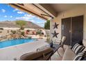 Relaxing covered patio overlooking a beautiful backyard with a custom pool and desert landscape at 6372 W Hill Ln, Glendale, AZ 85310