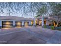 A well lit, large three-car garage and front entry is shown at dusk at 9041 N 46Th St, Phoenix, AZ 85028