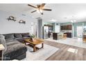 Open-concept living room featuring a gray sectional, wood floors, and seamless flow to the kitchen area at 4053 N 308Th Ln, Buckeye, AZ 85396