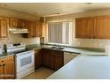 Functional kitchen featuring light wood cabinets, white appliances, and neutral countertops for meal preparation at , Tempe, AZ 85282