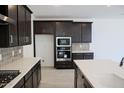 Well-equipped kitchen with dark wood cabinets, stainless steel appliances, tile backsplash, and white countertops at 2442 W Rowel Rd, Phoenix, AZ 85085