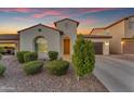 Charming single-story home boasts lovely landscaping and a warm, inviting entrance at dusk at 3938 E Ficus Way, Gilbert, AZ 85298