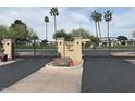 Gated entrance with a manicured lawn and mature palm trees at 3023 W Calavar Rd, Phoenix, AZ 85053