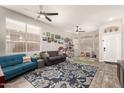 Bright living room featuring wood-look floors, multiple windows, ceiling fans, and a stylish area rug at 3668 E Cody Ave, Gilbert, AZ 85234
