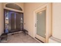 An entryway featuring a dark wood door, sidelight, security screen door, and a sitting bench at 11224 E Carol Ave, Scottsdale, AZ 85259