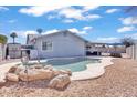 Backyard pool area with rock features, an outdoor dining set, and desert landscaping at 15814 N 62Nd Cir, Glendale, AZ 85306