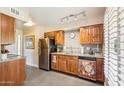 Well-lit kitchen showcasing stainless steel appliances, wooden cabinetry, tile backsplash, and modern track lighting at 17885 N 99Th Dr, Sun City, AZ 85373