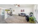 Bright living room featuring neutral carpet, two ceiling fans, and sliding glass doors leading to the outdoor area at 17885 N 99Th Dr, Sun City, AZ 85373
