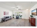 Bright living room with neutral carpet, ceiling fan, white walls, and a combination of carpet and tile flooring at 17885 N 99Th Dr, Sun City, AZ 85373