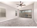 Bright bedroom with neutral walls, new carpet, ceiling fan, and sliding glass doors to backyard at 19726 W Woodlands Ave, Buckeye, AZ 85326