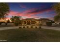 Front of home with manicured lawn, circular driveway, stone accents at twilight at 21470 E Orchard Ln, Queen Creek, AZ 85142