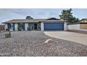 Inviting single-story home with gravel yard, a covered entry, and a blue two-car garage door at 815 E Paradise Ln, Phoenix, AZ 85022