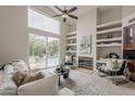 Cozy living room with fireplace, built-in shelves, and a large window overlooking the pool at 9442 N 118Th St, Scottsdale, AZ 85259