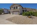 Two-story home featuring a three-car garage, desert landscaping, and a tile roof under a bright blue sky at 1758 N 74Th Pl, Mesa, AZ 85207