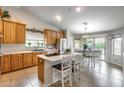Open kitchen and dining area with an island, wooden cabinets, stainless steel appliances, and backyard access at 11502 E Rafael Ave, Mesa, AZ 85212