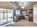 Well-lit kitchen features stainless steel appliances, dark wood cabinets, and a convenient sliding door to the backyard at 12048 W Dahlia Dr, El Mirage, AZ 85335