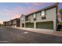 A row of townhomes with private garages, stucco exteriors, and balconies line a quiet neighborhood street at 1330 S Aaron -- # 218, Mesa, AZ 85209