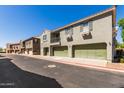 Townhouse complex with tidy landscaping, multiple garages, and a balcony under a clear blue sky at 1330 S Aaron -- # 218, Mesa, AZ 85209