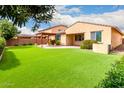 A spacious backyard with artificial turf, a covered patio, and desert landscaping provides a private retreat at 1437 E Flamingo Way, Gilbert, AZ 85297