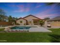 Backyard oasis featuring a private pool, green lawn, a covered patio and firepit perfect for outdoor entertaining at 18051 W Port Royale Ln, Surprise, AZ 85388