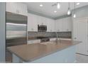 Modern kitchen featuring white cabinetry, stainless steel appliances, pendant lighting, and a spacious center island at 18051 W Port Royale Ln, Surprise, AZ 85388