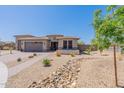 The exterior features neutral paint, a brick driveway, desert landscaping, and low-maintenance rock beds at 18159 W Piro St, Goodyear, AZ 85338