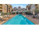 Community pool with lounge chairs surrounded by condo buildings under a sunny blue sky at 16 W Encanto Blvd # 2, Phoenix, AZ 85003