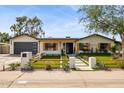 Charming home with modern landscaping, a dark garage door, rustic shutters, and a stone walkway to the front door at 4316 N 86Th Pl, Scottsdale, AZ 85251
