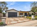Charming home with modern landscaping, a dark garage door, rustic shutters, and a decorative, geometric driveway at 4316 N 86Th Pl, Scottsdale, AZ 85251