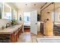 Elegant bathroom featuring a stone shower, dual vanity, and view into the primary bedroom at 13802 N 64Th Pl, Scottsdale, AZ 85254