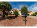 Well-manicured front yard featuring desert landscaping with decorative rock and mature trees at 12930 W Chapala Dr, Sun City West, AZ 85375